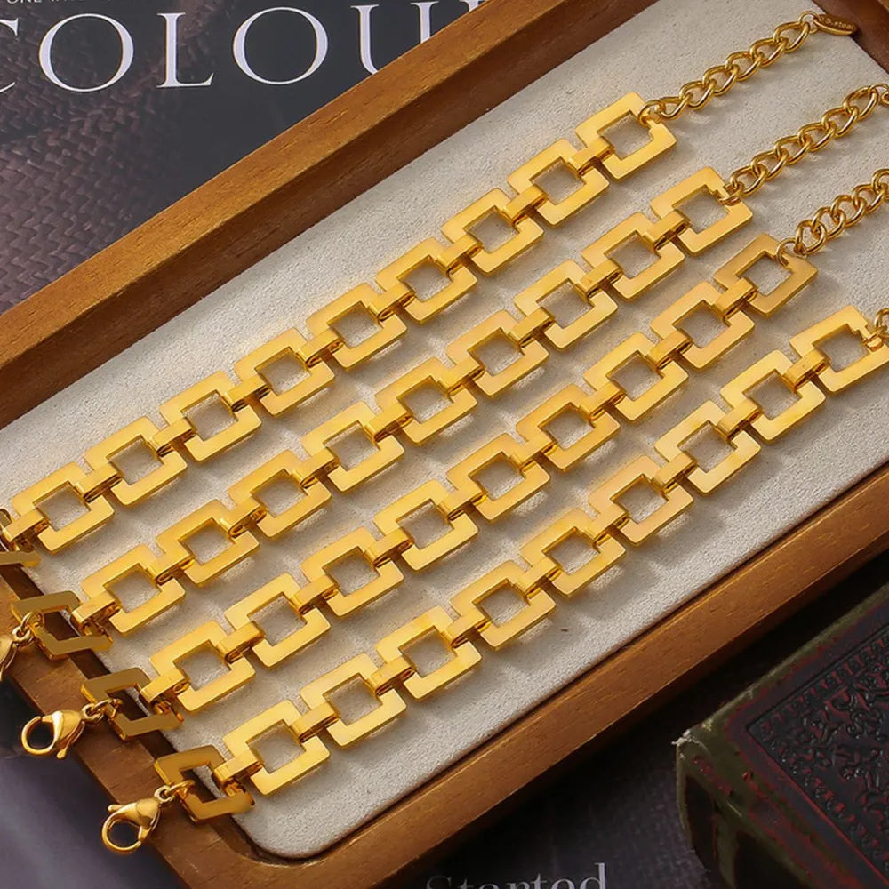 Geometric link bracelet in gold with square links and a curb chain accent.