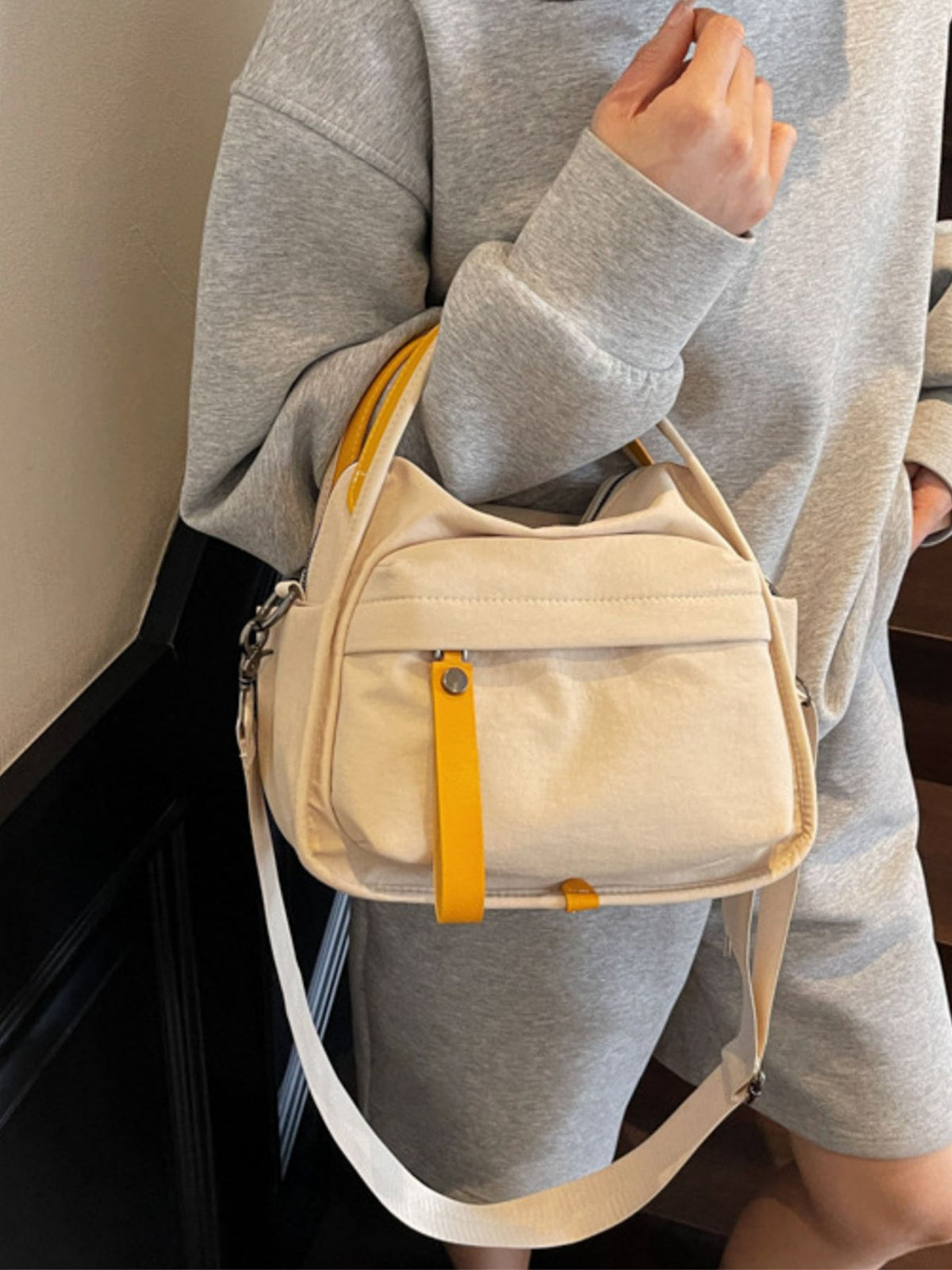 Khaki crossbody bag with yellow pull tab and strap, casual style.