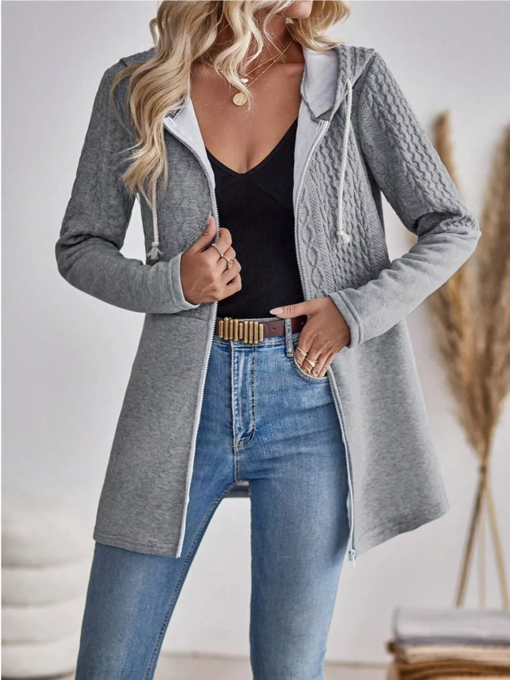 Grey cable-knit hooded zip jacket with white drawstring and zipper.