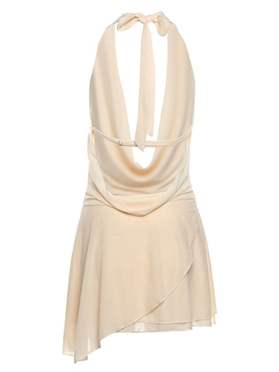 Backless mini dress with halter tie, cowl neck, and asymmetrical wrap skirt in cream.