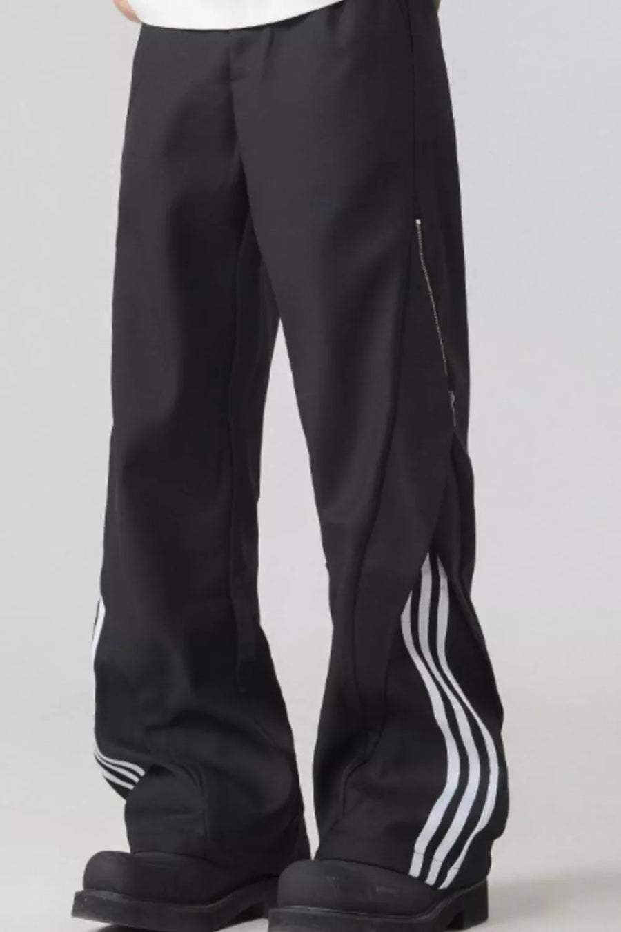 Black wide-leg sweatpants with white side stripes and a zipper detail.