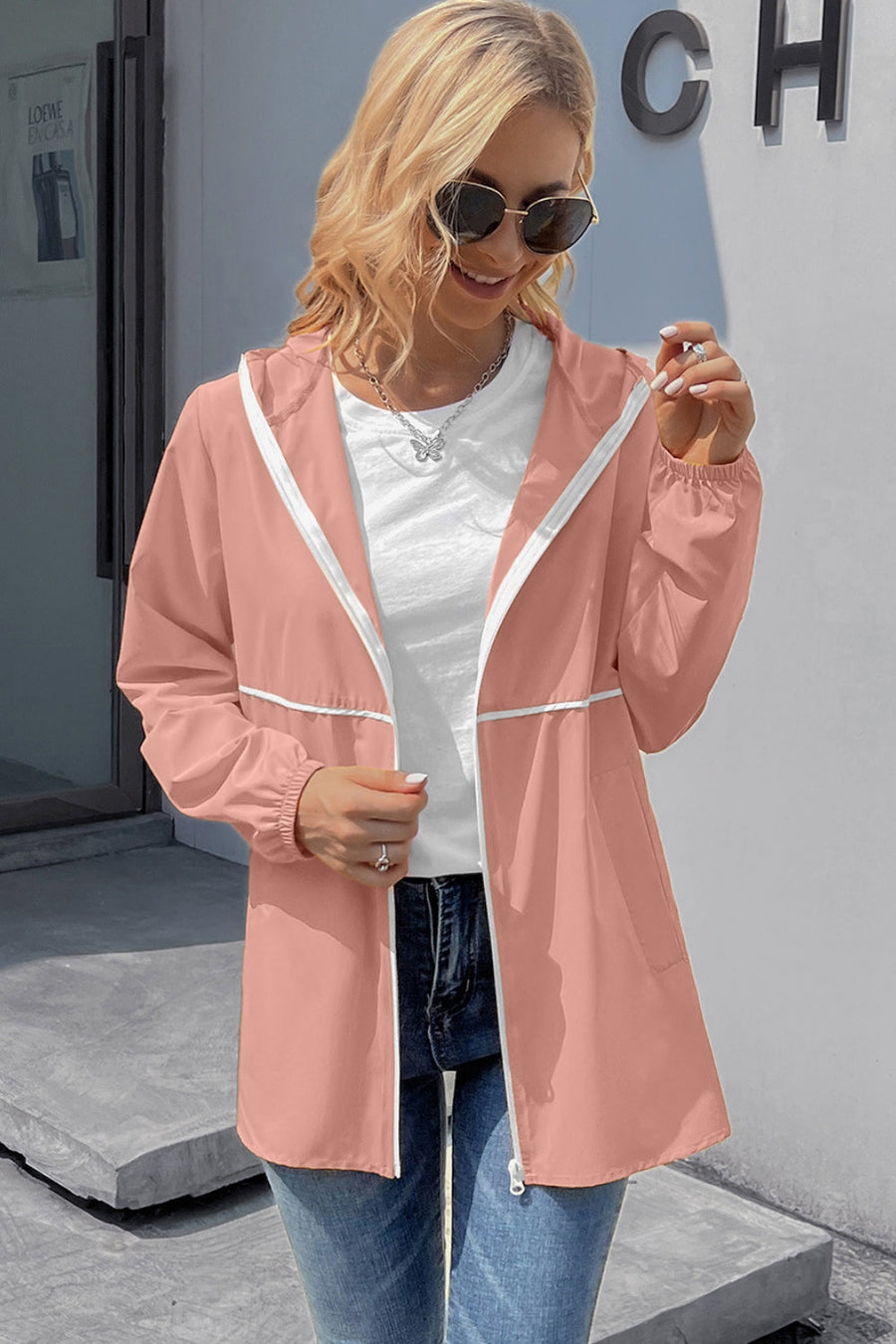 Blush pink hooded rain jacket with white trim and zipper, elastic cuffs.
