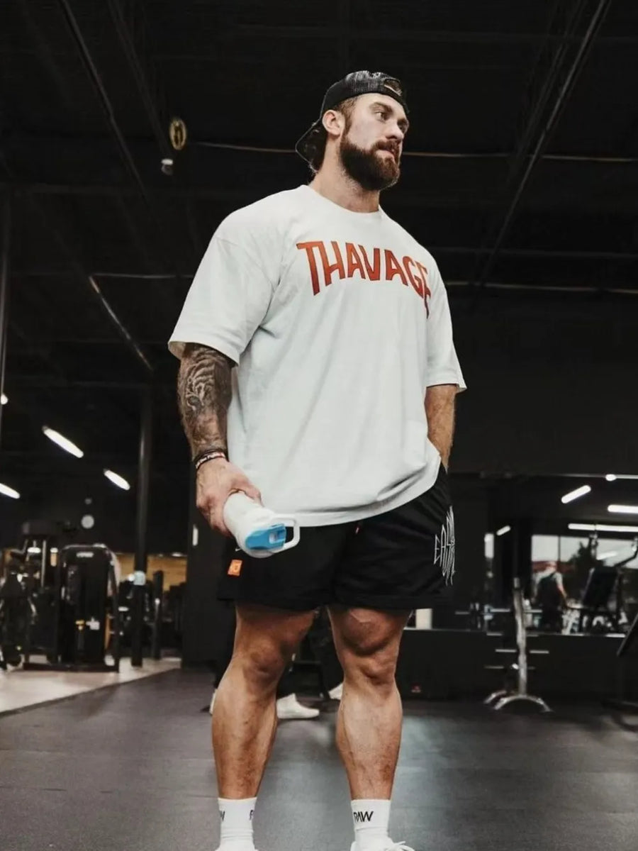 White oversized graphic tee with red "THAVAGE" print, crew neck, short sleeves.