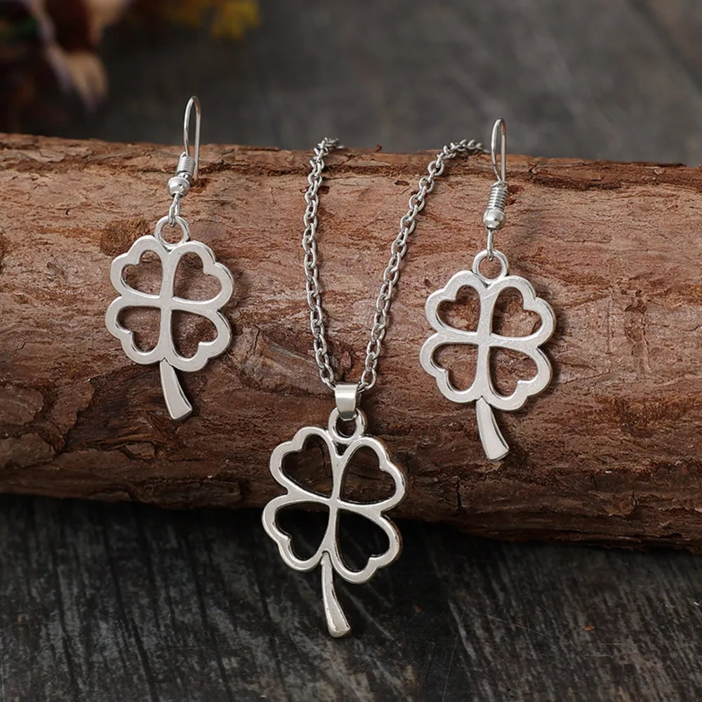 Silver four-leaf clover pendant necklace and matching dangle earrings jewelry set.