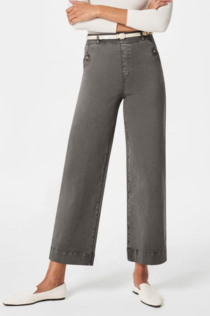 Wide-leg utility denim trousers in dark gray with button details and a white belt.