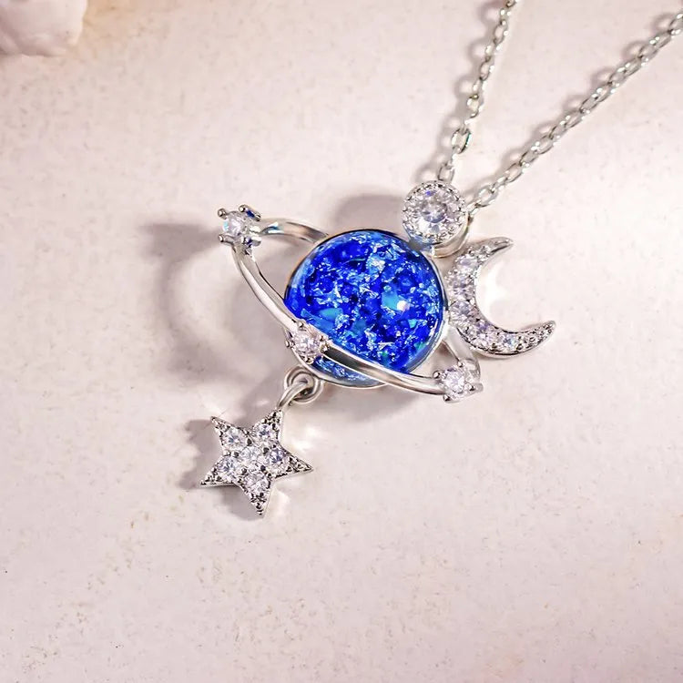 Silver celestial necklace with blue cosmic orb, moon, and star charms.