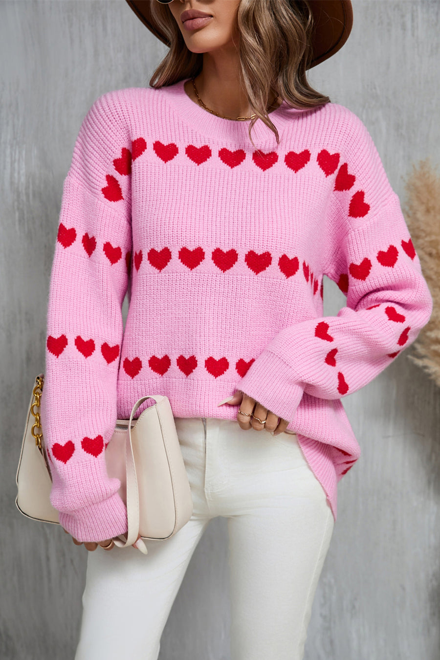 Pink knit pullover sweater with red heart stripe pattern, crew neck, and long sleeves.