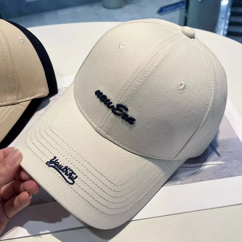 Off white baseball cap with navy blue embroidered "new Era" and "Youthful" text.