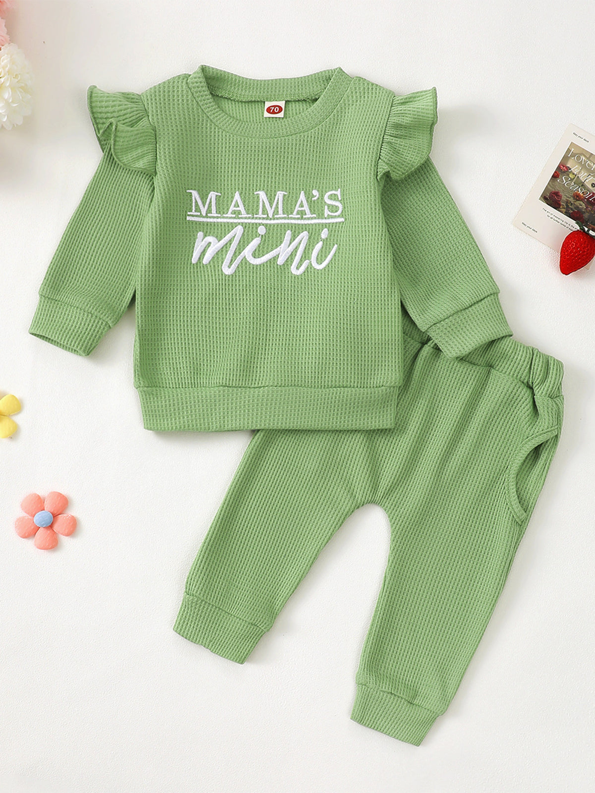 Green waffle knit toddler top with ruffled sleeves and "Mama's Mini" graphic, paired with matching pants.
