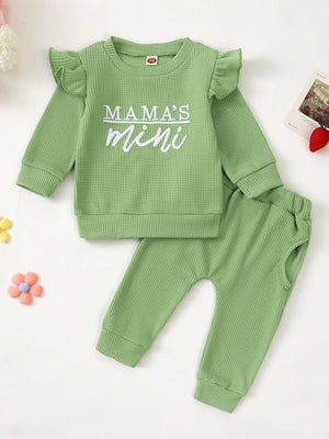 Green waffle knit toddler top with ruffled sleeves and "Mama's Mini" graphic, paired with matching pants.