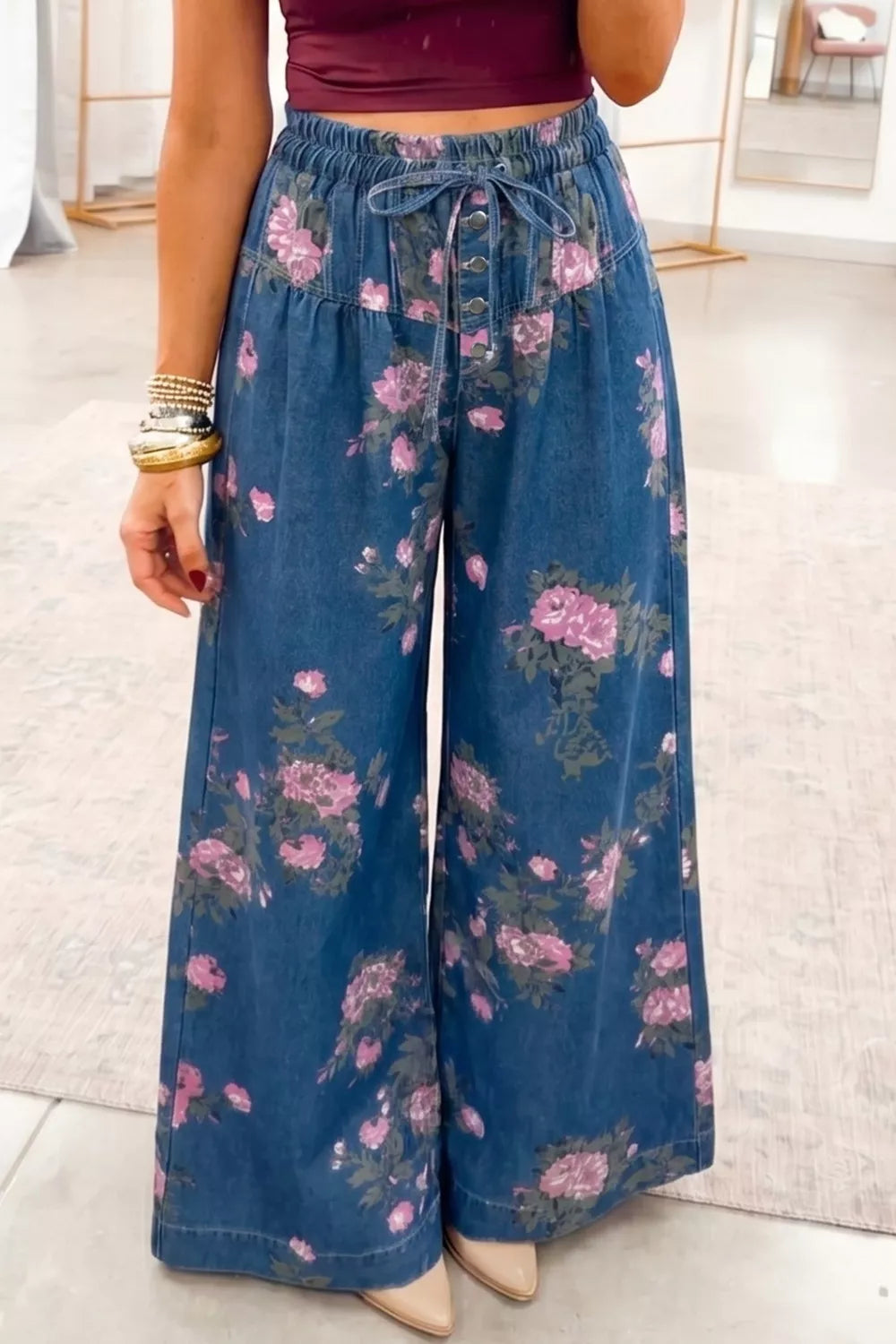 Floral print high-waisted wide-leg jeans in blue denim with button front and tie waist.