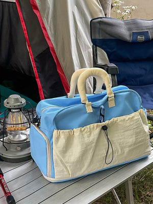 Blue crinkled nylon travel bag with drawstring pockets and padded handles.