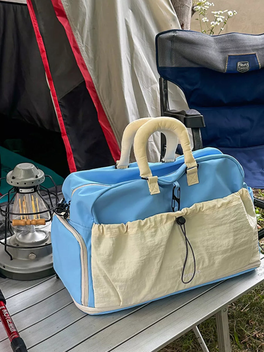 Blue crinkled nylon travel bag with drawstring pockets and padded handles.