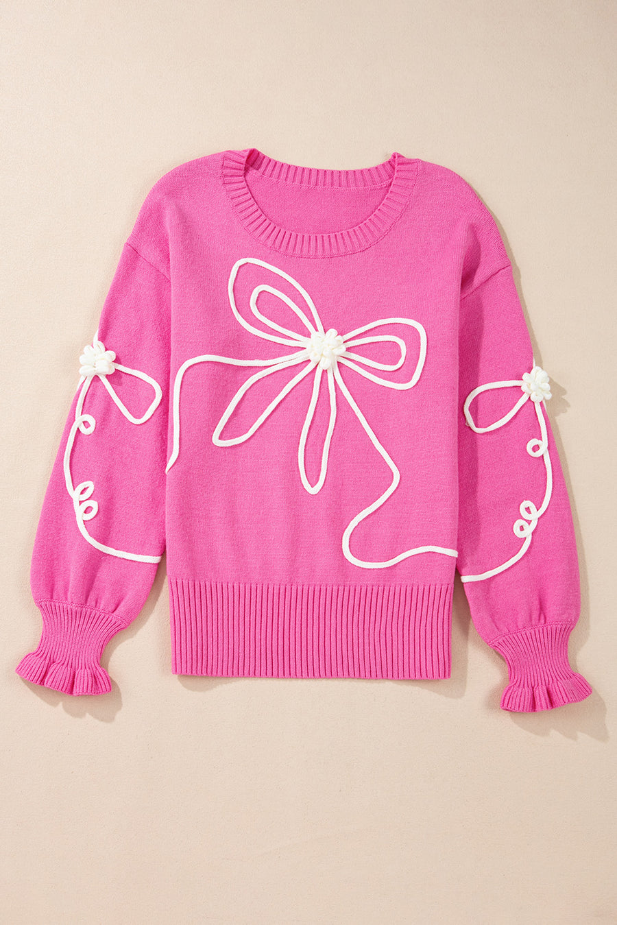 Fuchsia pink knit sweater with white embroidered bow motif and ruffled cuffs.