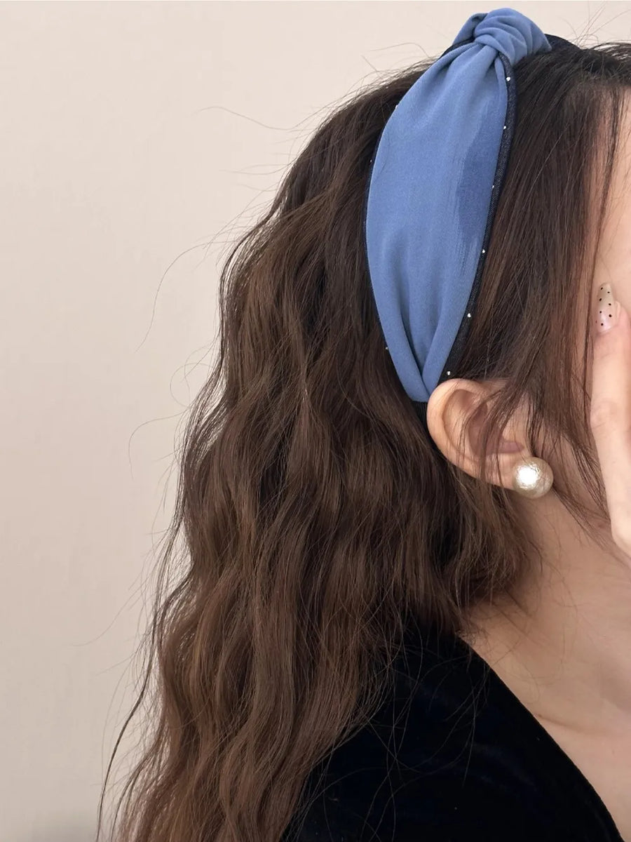 Denim knot headband with crystal detail in medium blue, styled with wavy hair.