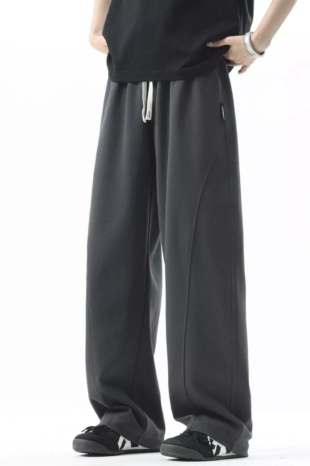 Men's dark gray loose fit sweatpants with drawstring and curved seam detail.