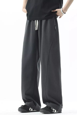 Men's dark gray loose fit sweatpants with drawstring and curved seam detail.