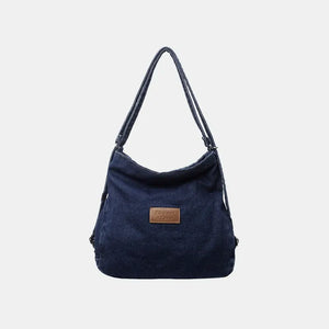 Denim hobo bag in dark blue with leatherette patch and adjustable straps.