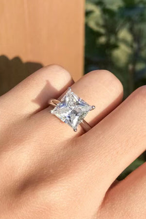 Silver ring with a bright princess cut solitaire diamond on a hand.