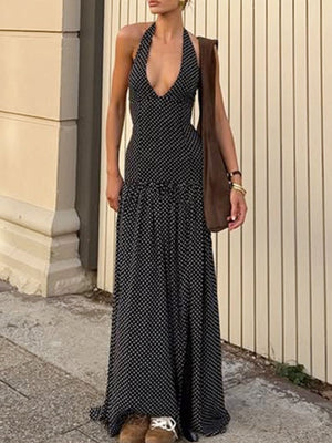 Black polka dot halter neck maxi dress with a deep V-neck and tiered skirt.