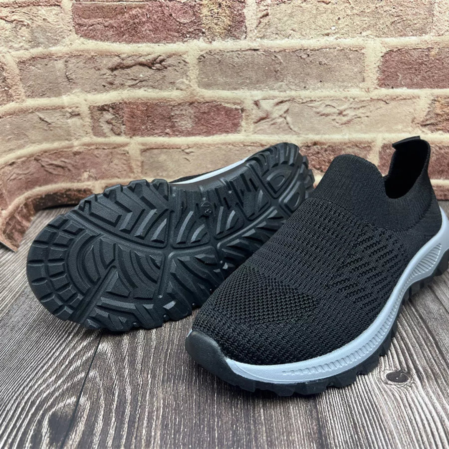Black breathable knit slip-on sneakers with grey soles and textured tread.