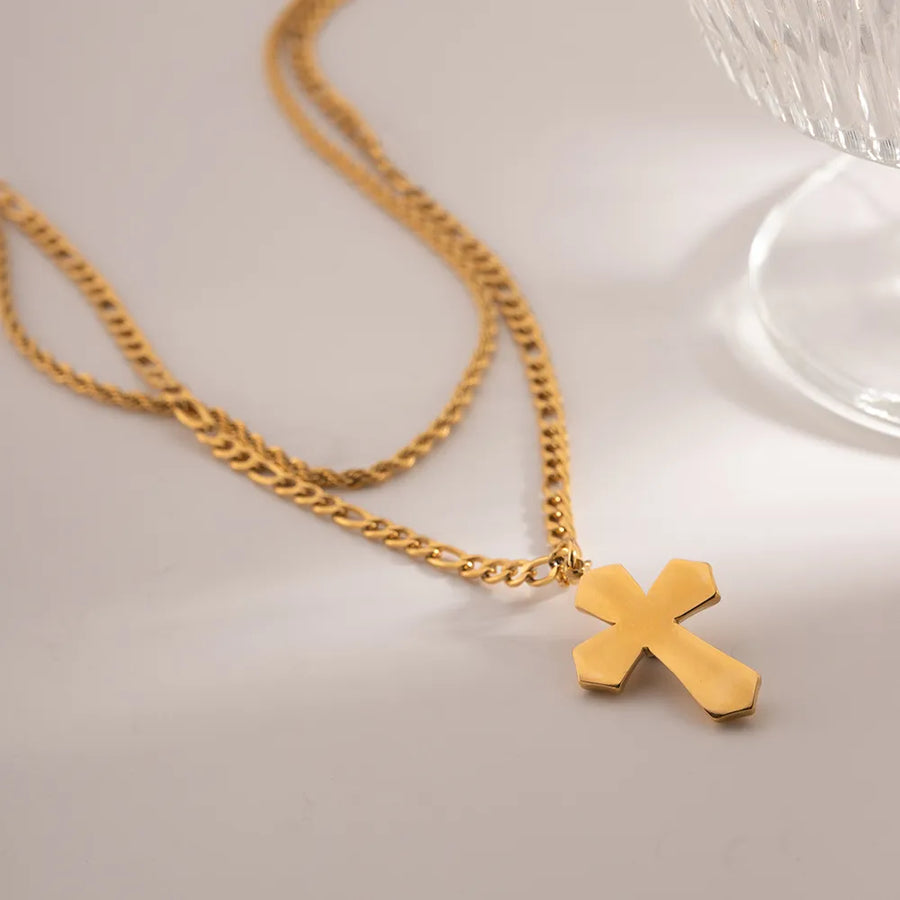 Gold layered chain necklace with a sculpted cross pendant.