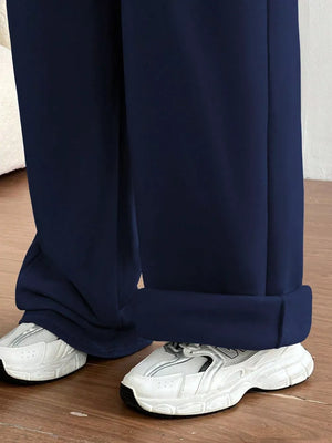 Dark blue wide-leg maternity joggers with cuffed hems and white sneakers