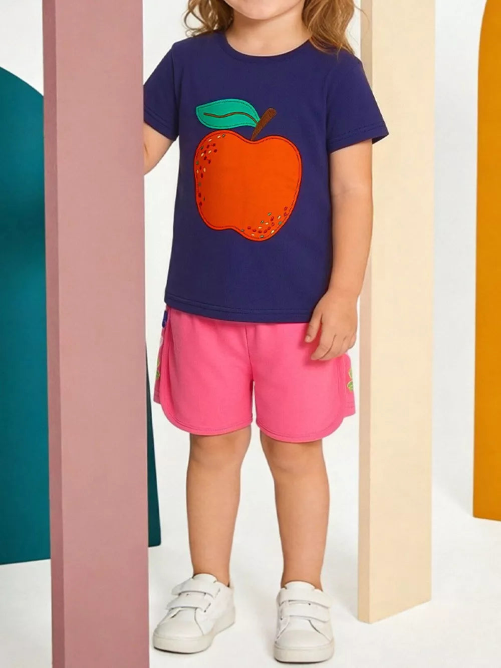Toddler navy t-shirt with orange apple appliqué and pink shorts set.