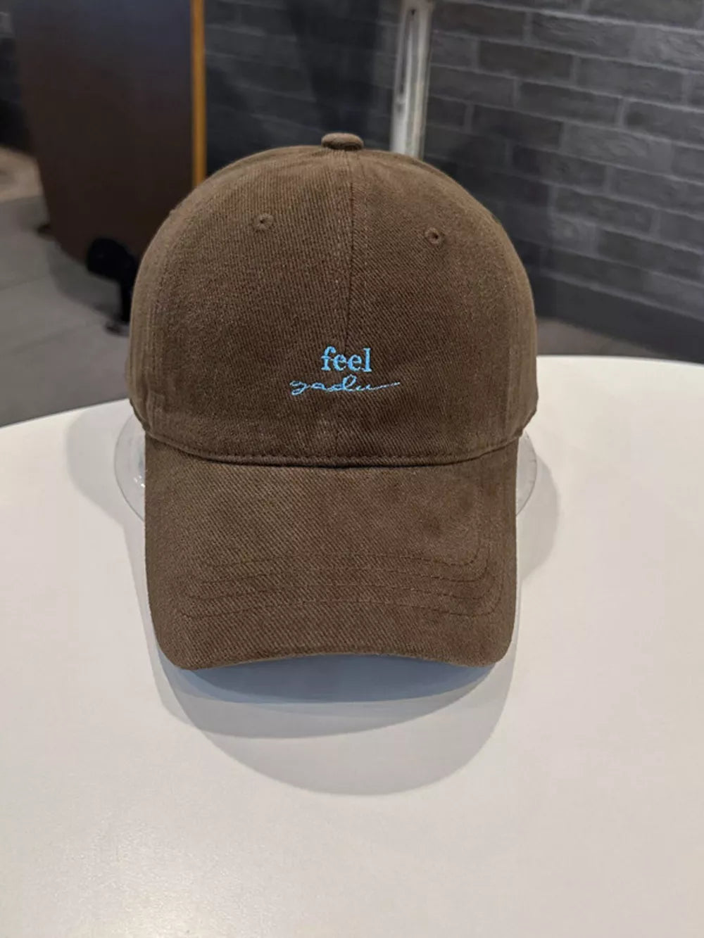 Brown baseball cap with blue embroidered text detail