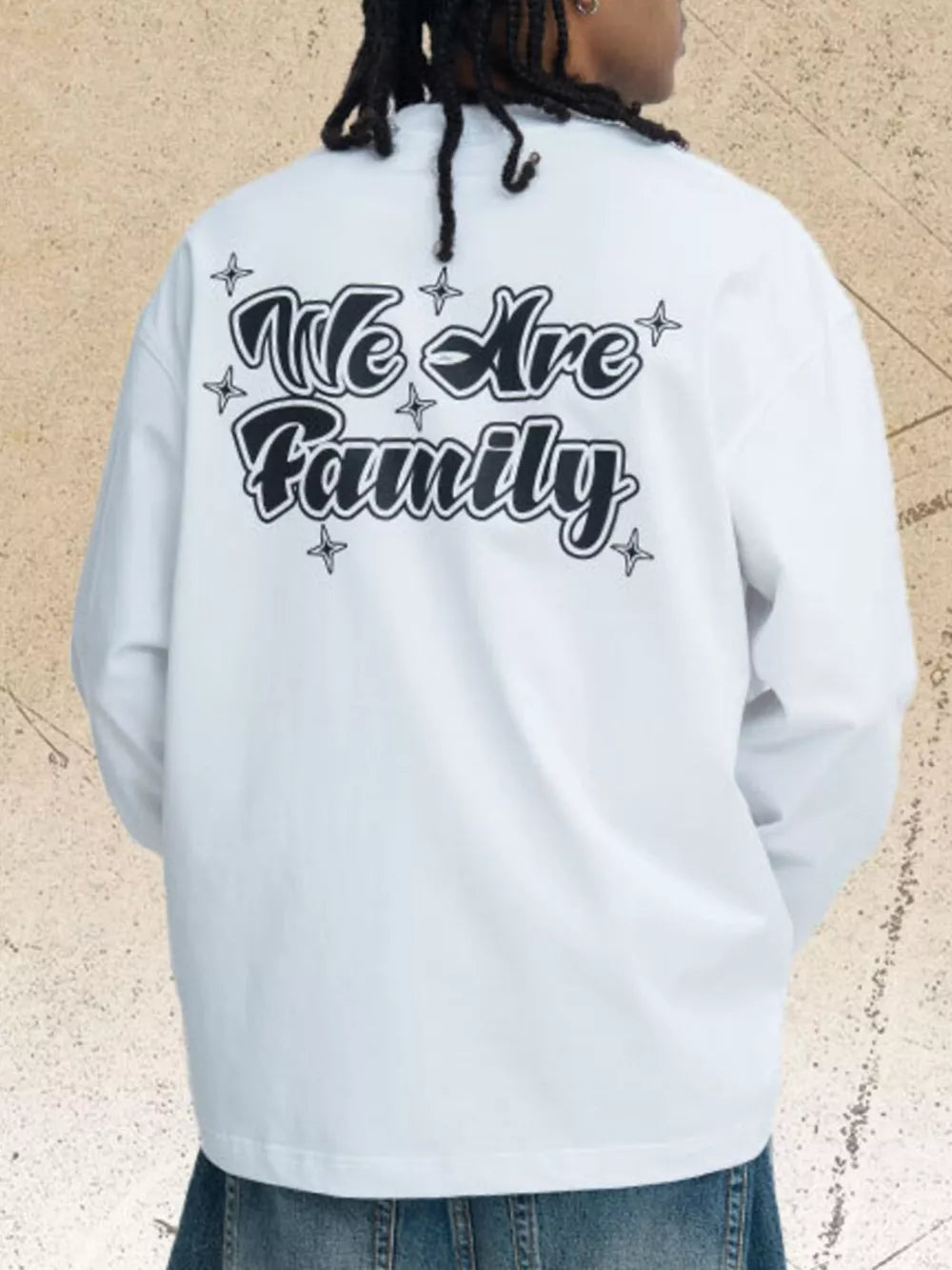 White long sleeve tee with black "We Are Family" graphic print and star accents