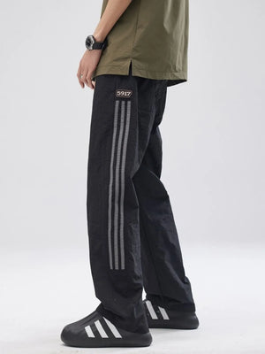 Black drawstring sweatpants with side stripe detail and logo patch