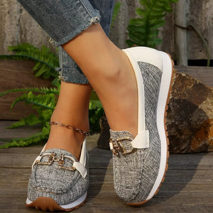 Round toe slip-on loafers with gold buckle detail and white trim.