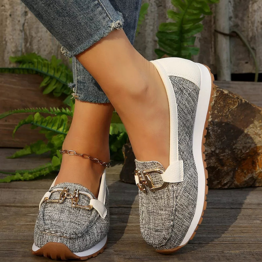 Round toe slip-on loafers with gold buckle detail and white trim.