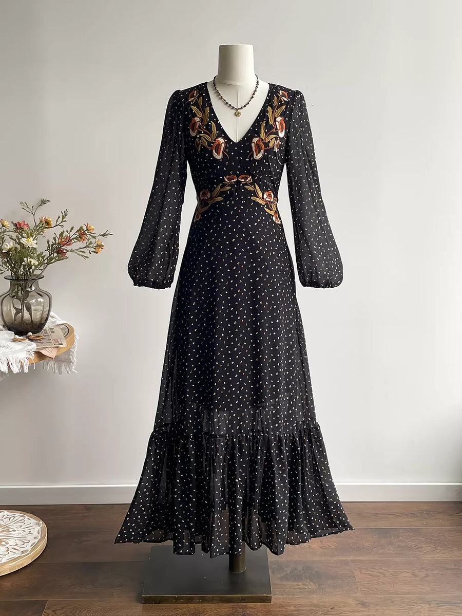 Black polka dot maxi dress with embroidered floral detail, V-neck, long sleeves, and ruffled hem.