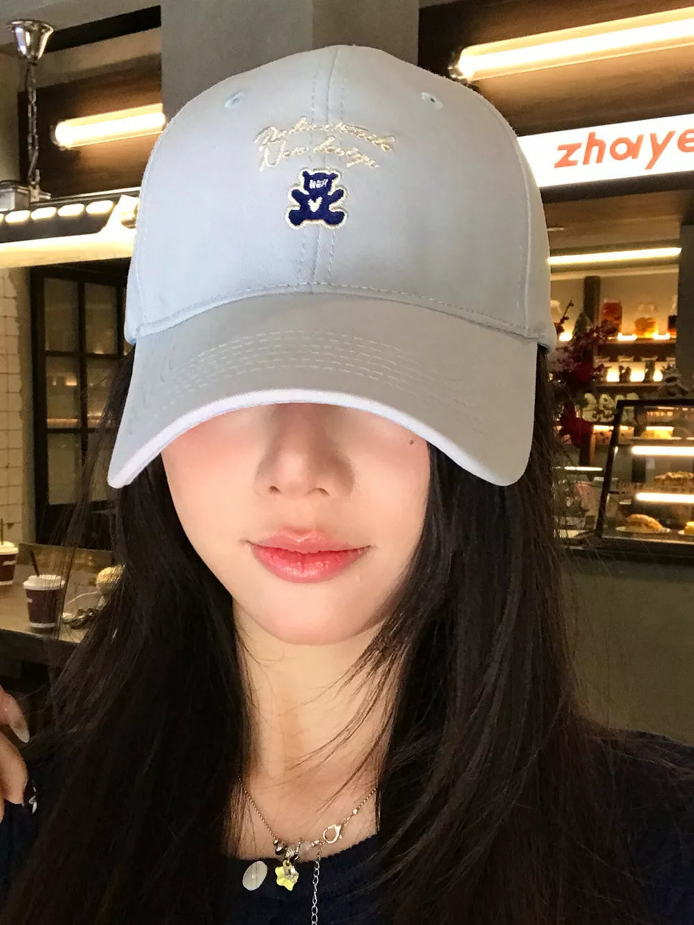 Light blue baseball cap with embroidered teddy bear and script text.