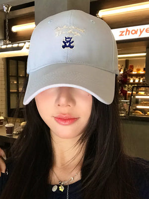 Light blue baseball cap with embroidered teddy bear and script text.