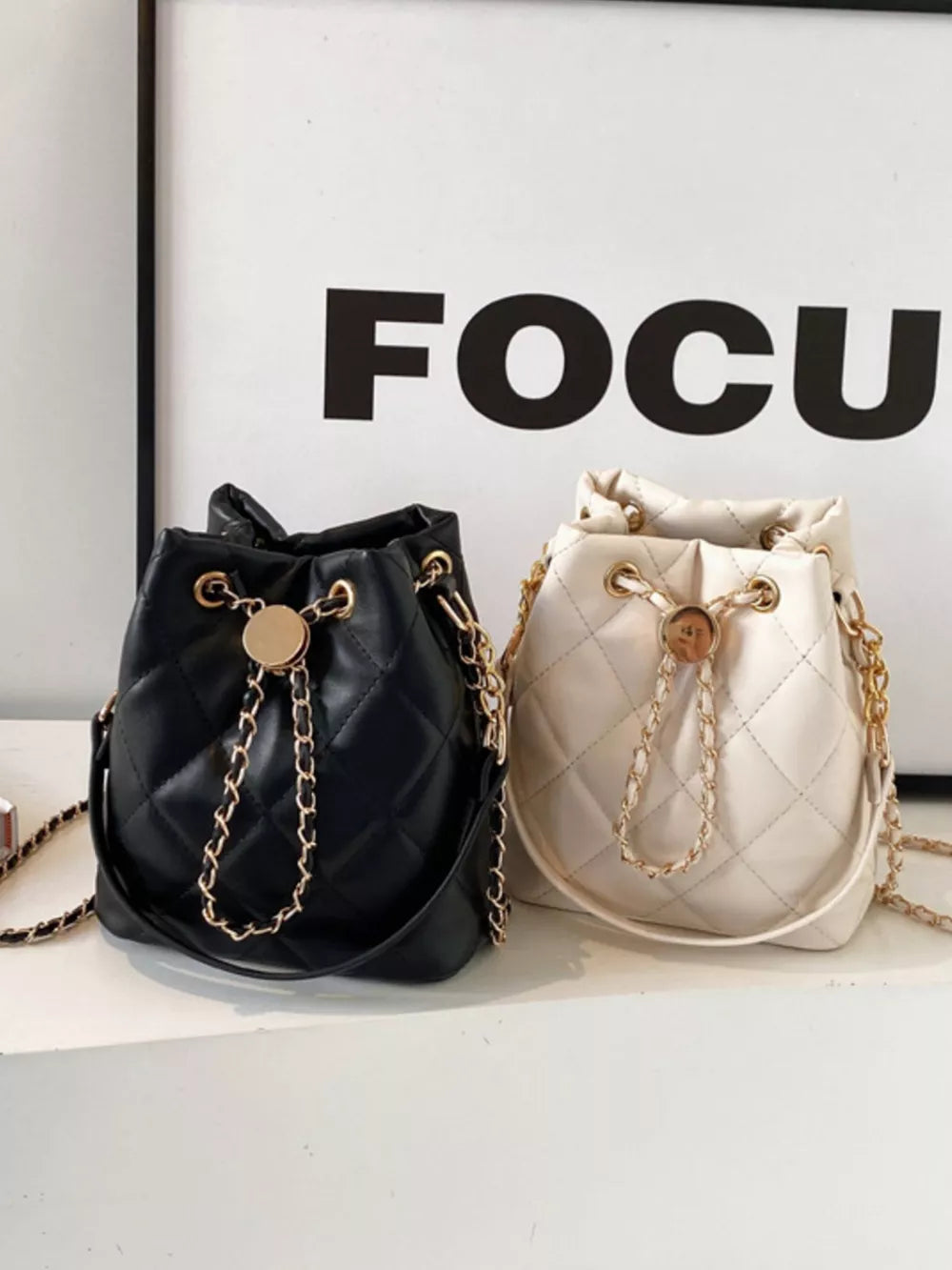 Chic quilted bucket crossbody bag in black and white with gold chain detail.