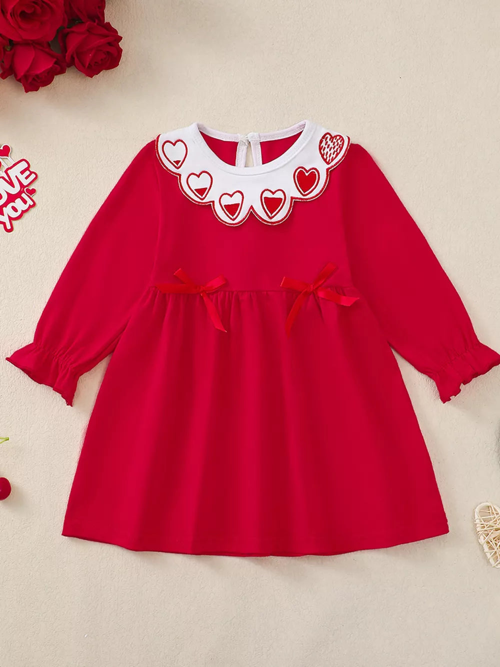 Red baby dress with heart embroidered collar, bows, and ruffled cuffs.