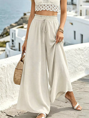 Cream linen wide-leg pants with drawstring waist and ruffled detail.