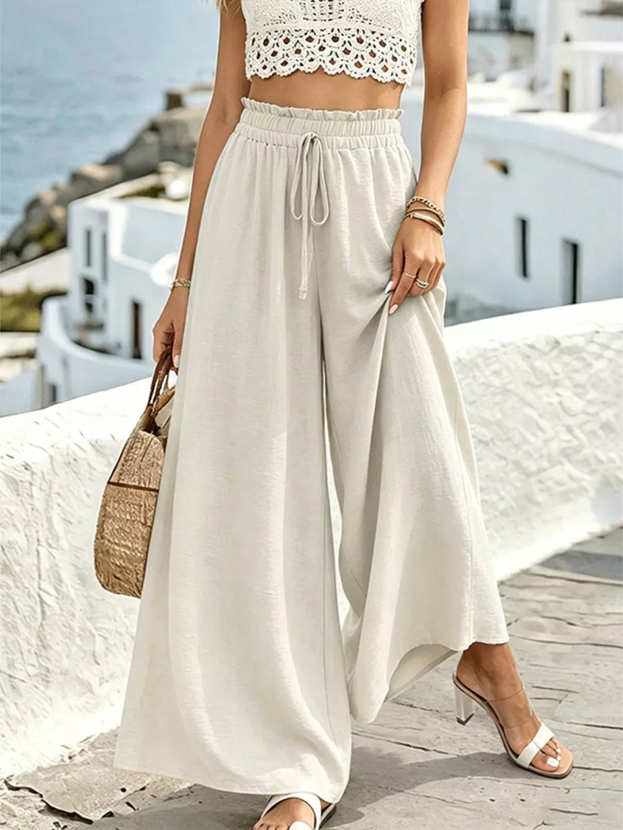 Cream linen wide-leg pants with drawstring waist and ruffled detail.