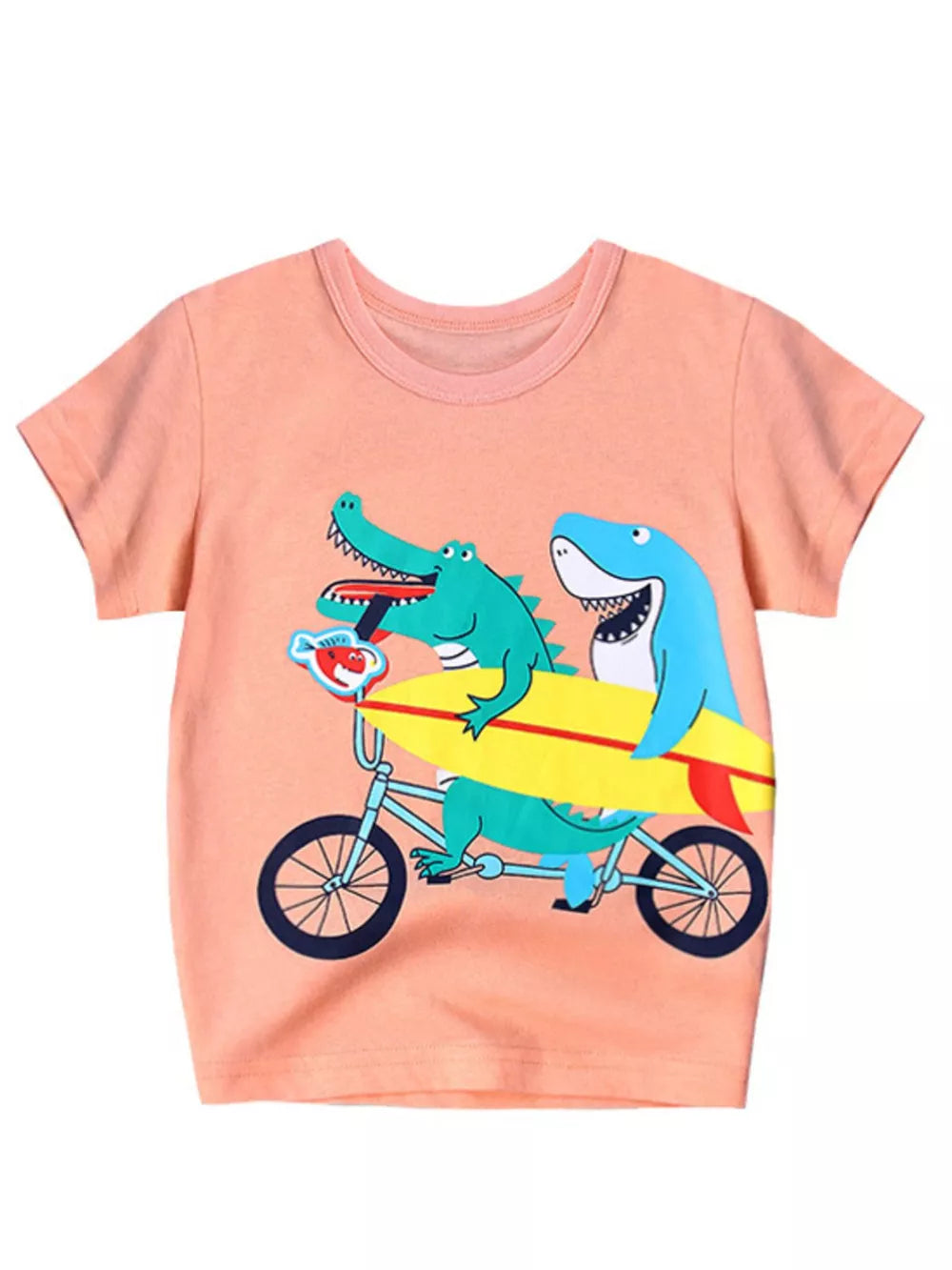 Peach t-shirt with short sleeves and a graphic of a crocodile and shark riding a bicycle with a surfboard.
