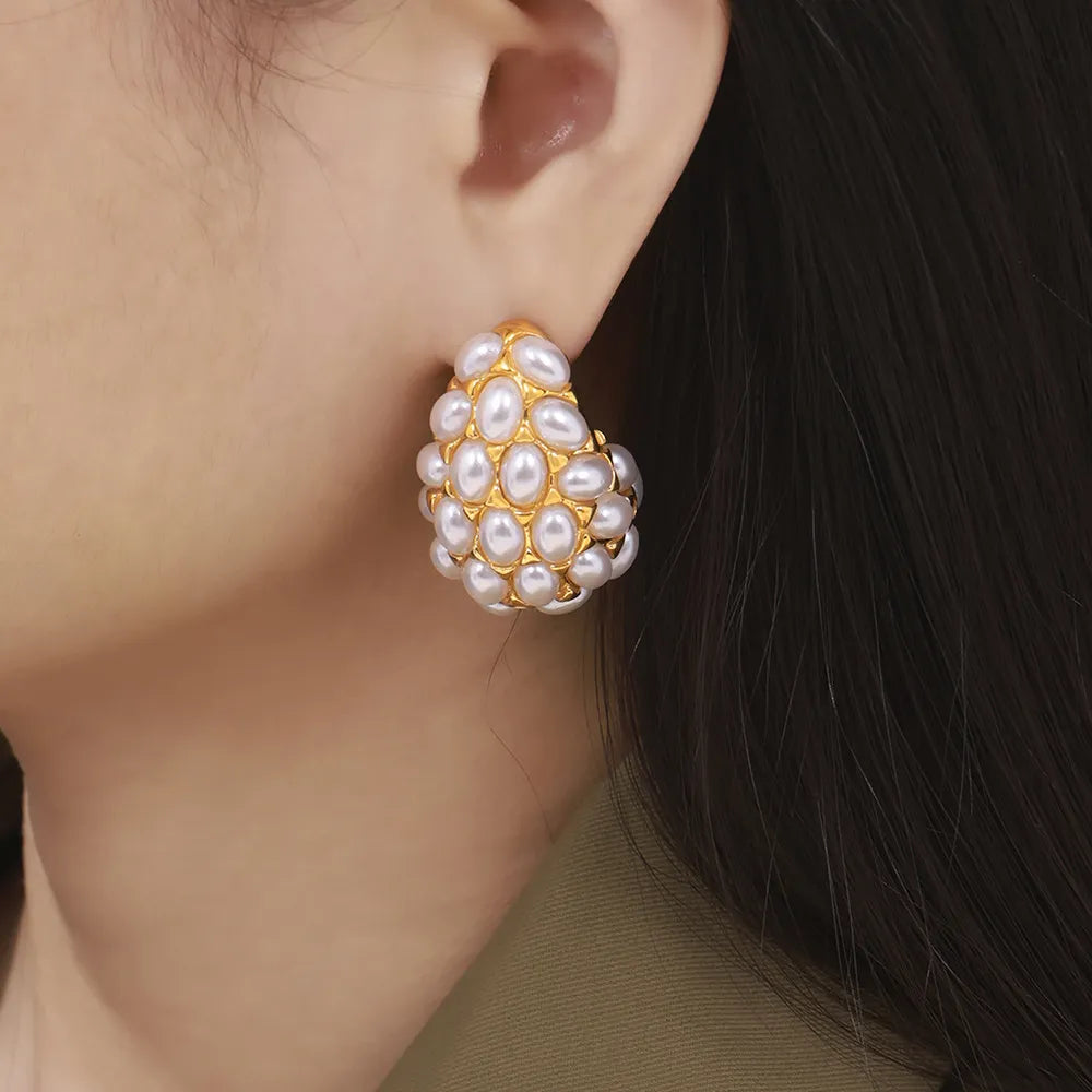 Gold sculptural earrings with a cluster of white pearls.
