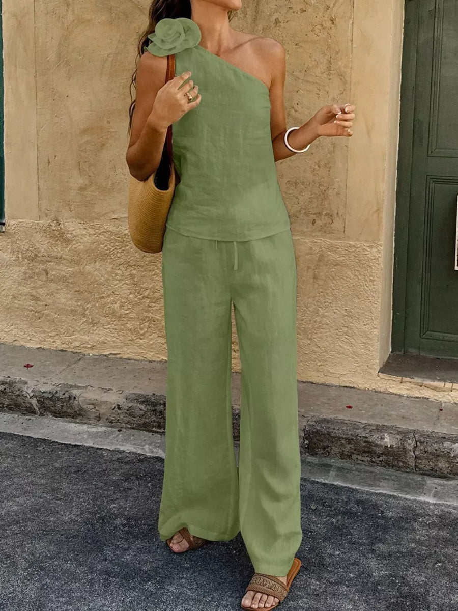 Mint green cotton one-shoulder top with floral embellishment and wide-leg pants.