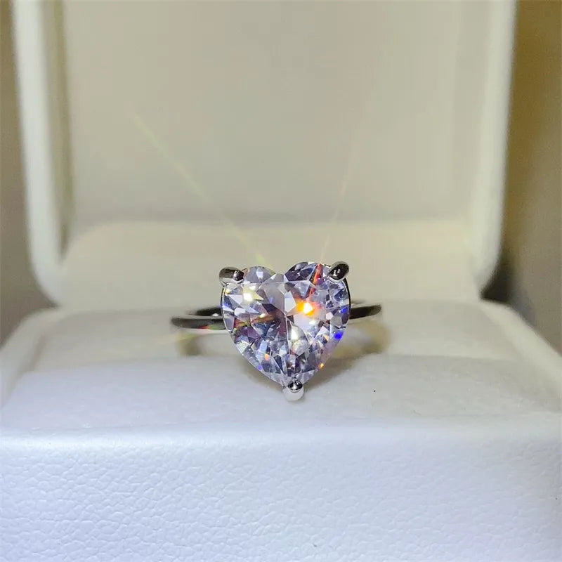 Silver ring with a large, clear heart-cut moissanite solitaire stone.