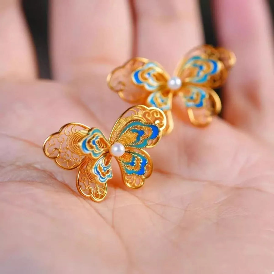 Gold butterfly stud earrings with blue enamel and pearl detail