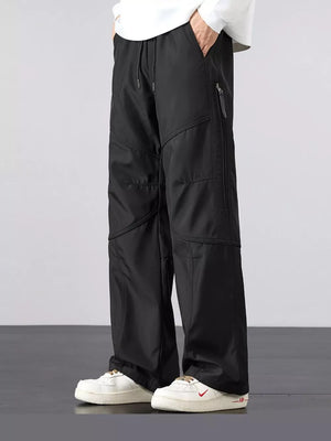 Men's black loose fit cargo pants with drawstring and zippered pockets.