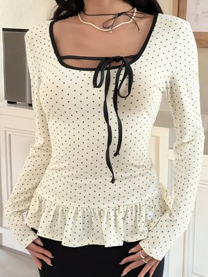 Ruffled polka dot long-sleeve t-shirt with black trim and tie-neck detail.