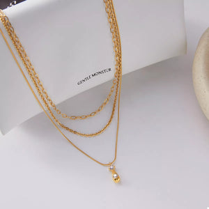 Gold three layered pendant necklace with delicate chains and a small diamond accent.