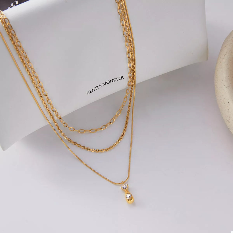 Gold three layered pendant necklace with delicate chains and a small diamond accent.