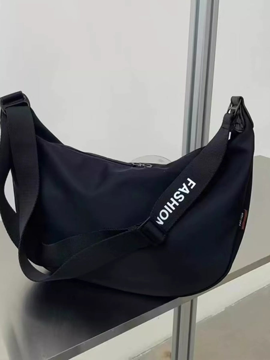 Black crossbody bag with adjustable strap and white "FASHION" text detail.